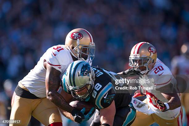 Donte Whitner of the San Francisco 49ers attempts to tackle Greg Olsen of the Carolina Panthers during the NFC Divisional Playoff Game between the...