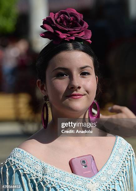 Women wearing the traditional flamenco dresses, often in bright colors, and accessorized with flower in hair dance around casetas at the 'Feria de...