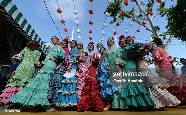 Women wearing the traditional flamenco dresses, often in bright colors, and accessorized with flower in hair dance around casetas at the 'Feria de...