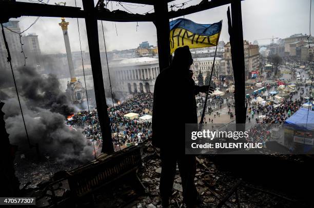 Protester holds an Ukranian national flag from a burned building during a face-off against police on February 20, 2014 in Kiev. Ukraine's embattled...