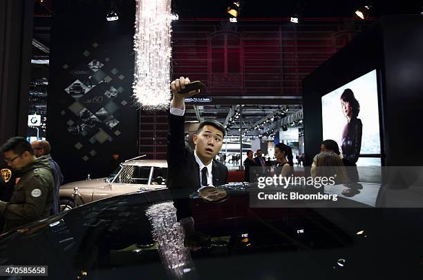 Man takes a photograph of a PSA Peugeot Citroen DS5 vehicle at the 16th Shanghai International Automobile Industry Exhibition in Shanghai, China, on...