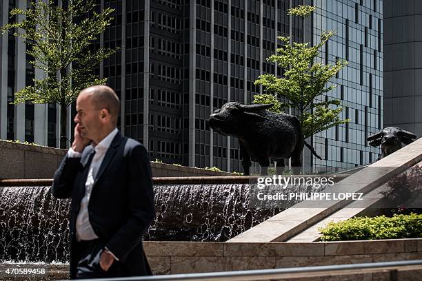 HongKong-China-economy-stocks,FOCUS by Aaron TAM This picture taken on April 16, 2015 shows a man talking on a mobile phone as he walks past two bull...