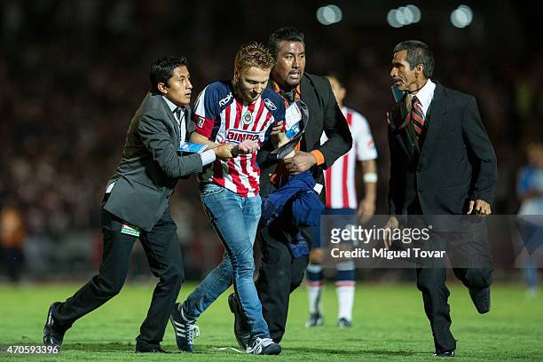 Fan of Chivas is scorted by security during a Championship match between Puebla and Chivas as part of Copa MX Clausura 2015 at Olimpico Universitario...