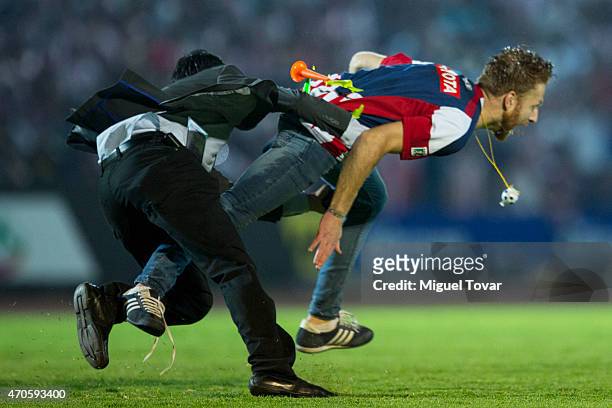 Fan of Chivas is tackled after invading the pitch during a Championship match between Puebla and Chivas as part of Copa MX Clausura 2015 at Olimpico...