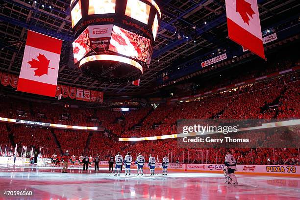 Teammates of the Vancouver Canucks and Calgary Flames stand for the national anthem ceremony before the game at Scotiabank Saddledome for Game Four...