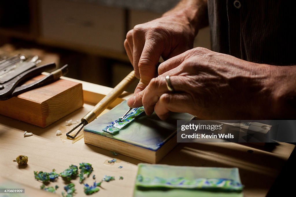 Artist's hands working on art piece with tools