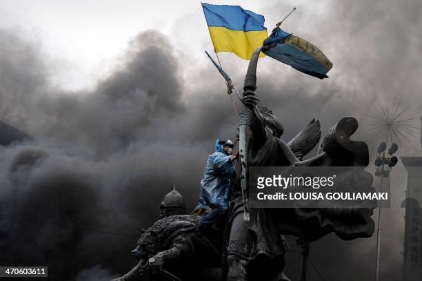 An anti-government protester sits on the Founders of Kiev monument during clashes with riot police in central Kiev on February 20, 2014. At least 25...