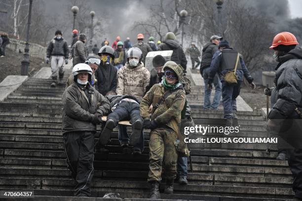 Protesters carry a wounded demonstrator in Kiev on February 20, 2014. Hundreds of armed protesters charged police barricades Thursday on Kiev's...