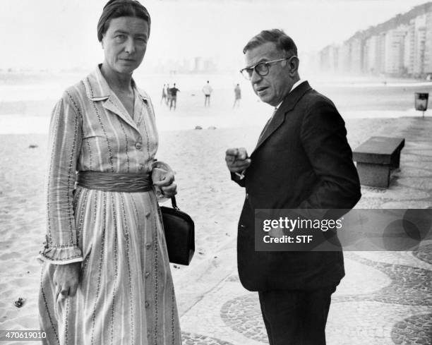 French writers and philosophers, Simone de Beauvoir and Jean-Paul Sartre take a walk on Copacabana beach in Rio, September 21, 1960. AFP PHOTO