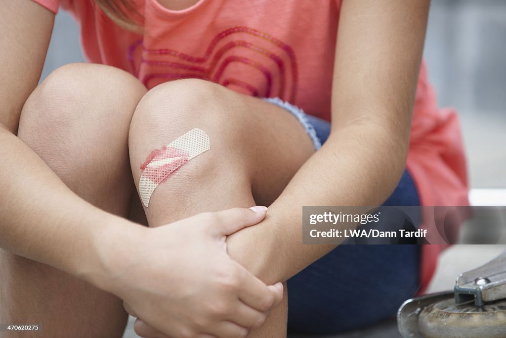 Caucasian girl with lipstick kiss over bandage on knee
