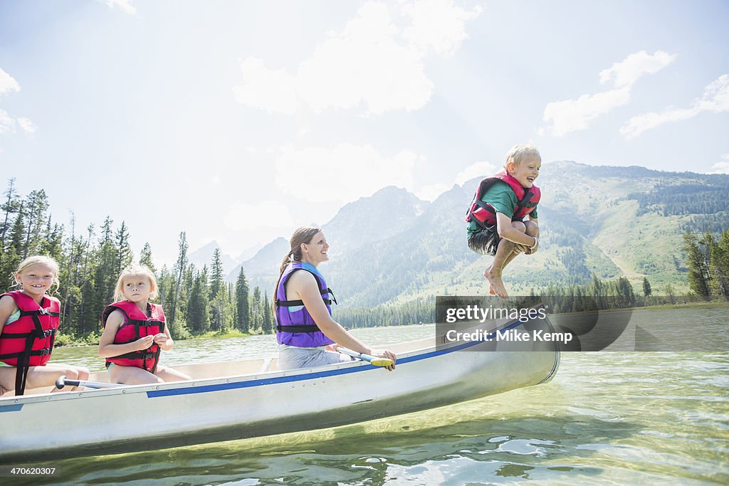 Caucasian boy jumping from canoe into lake