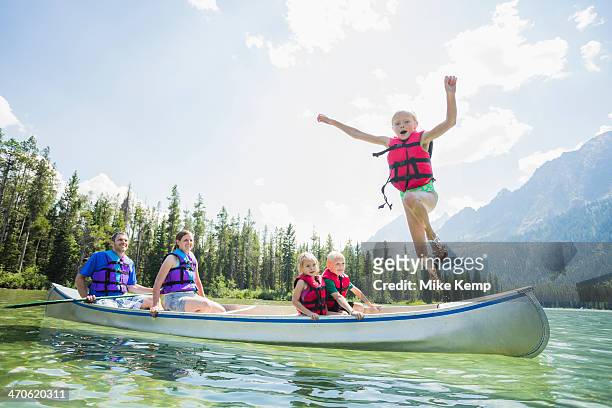 caucasian boy jumping from canoe into lake - jumping of boat photos et images de collection