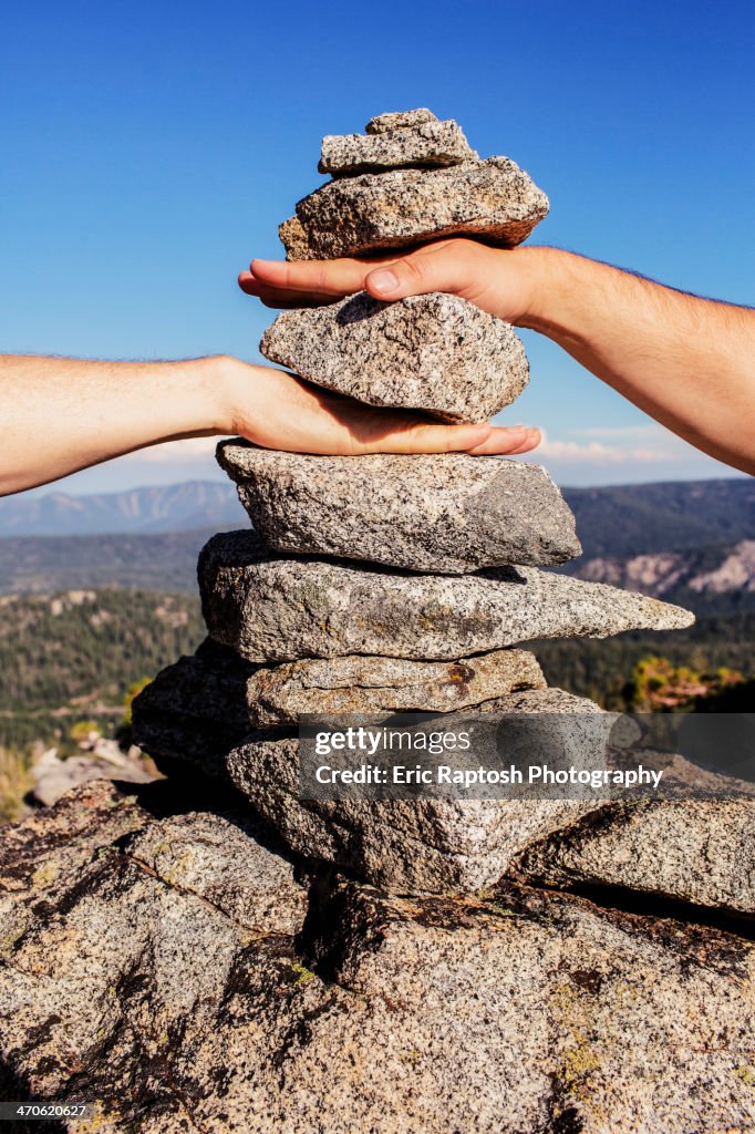 Caucasian couple stacking their hands in rocks