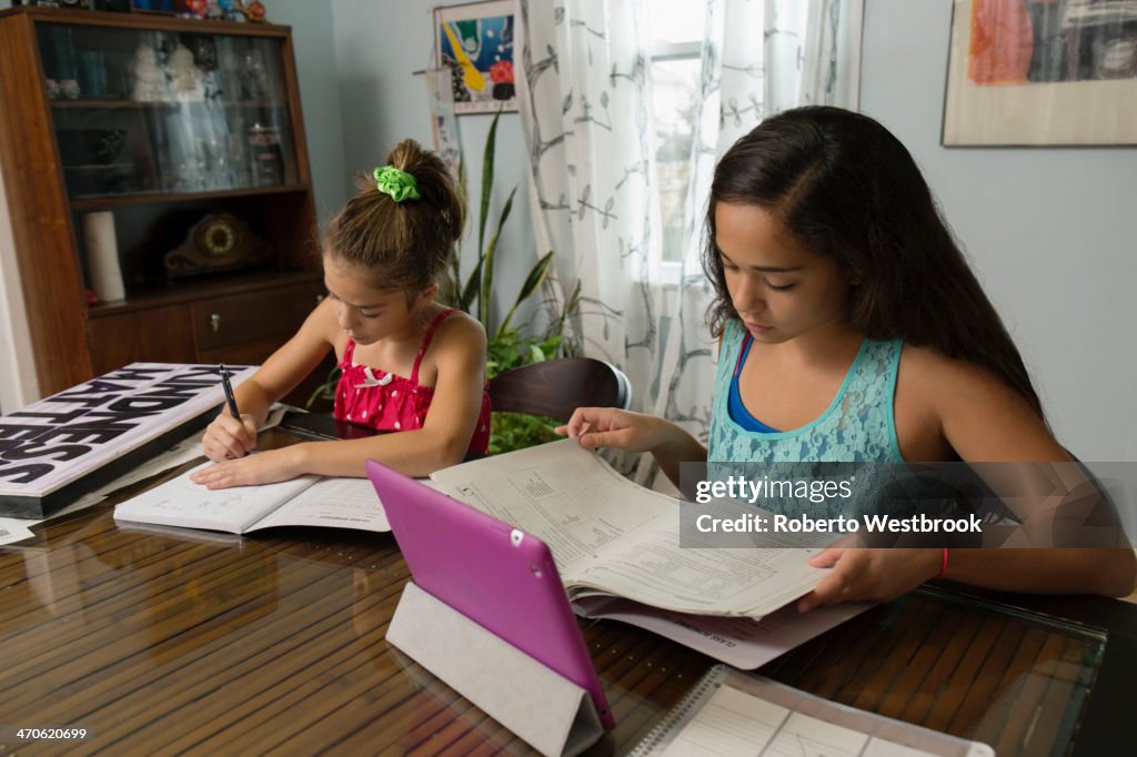 Mixed race sisters doing homework at table