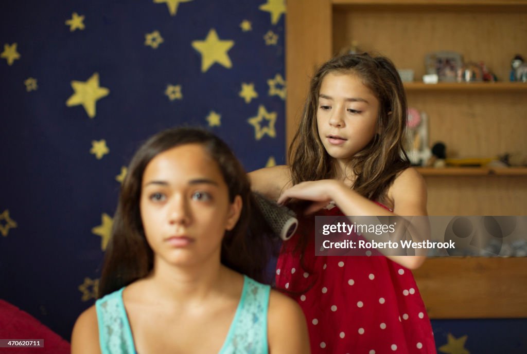 Mixed race girl brushing sister's hair