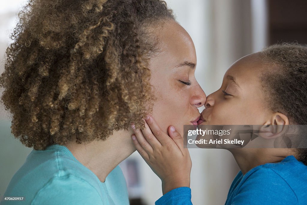 Black mother and daughter kissing