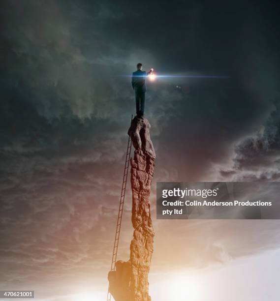 caucasian man with lantern on rocky pillar - optimistic inspiring movement stock pictures, royalty-free photos & images