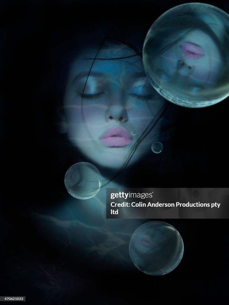 Mixed race woman's face reflected in bubbles