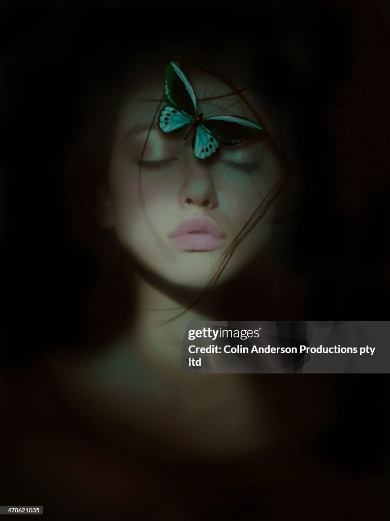 Butterfly perched on mixed race woman's face