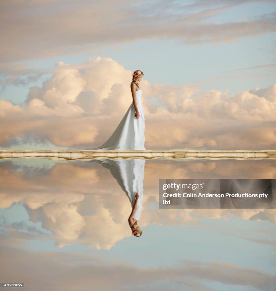 Caucasian bride reflected in still lake