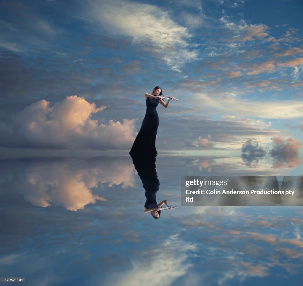 Caucasian woman with violin reflected in still lake