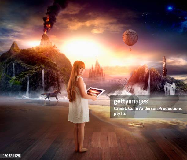 caucasian girl using digital tablet in dramatic landscape - fantasy stock-fotos und bilder