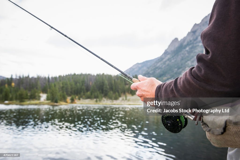 Caucasian fisherman holding rod in river