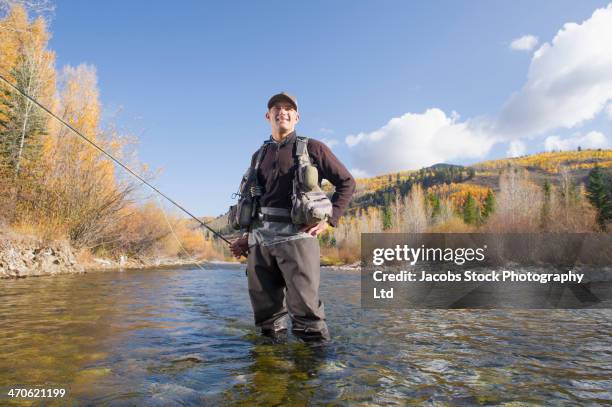 caucasian fisherman smiling in river - ウェーダー ストックフォトと画像