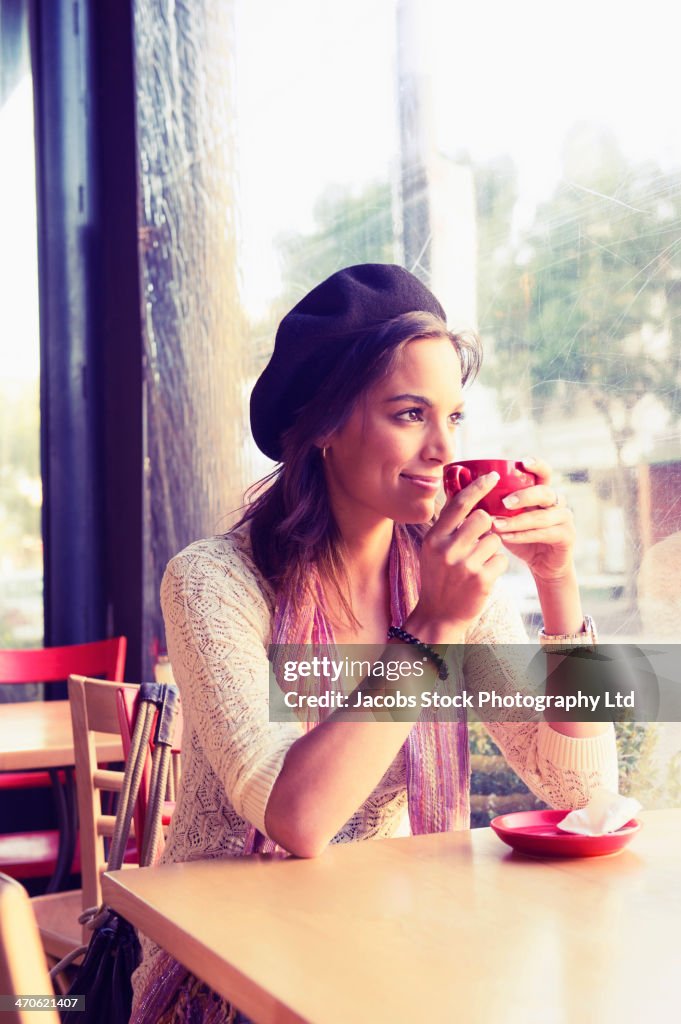 Mixed race woman having coffee in cafe