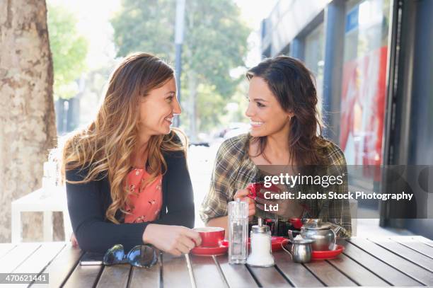 mixed race women having tea at sidewalk cafe - mixed race woman drinking tea stock-fotos und bilder