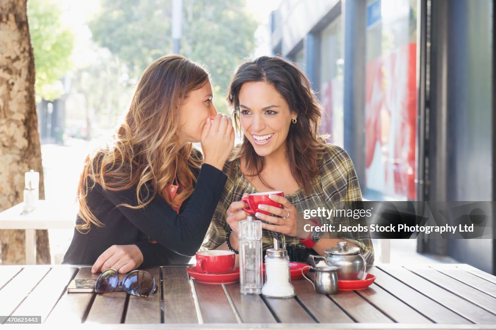 Mixed race women having tea at sidewalk cafe