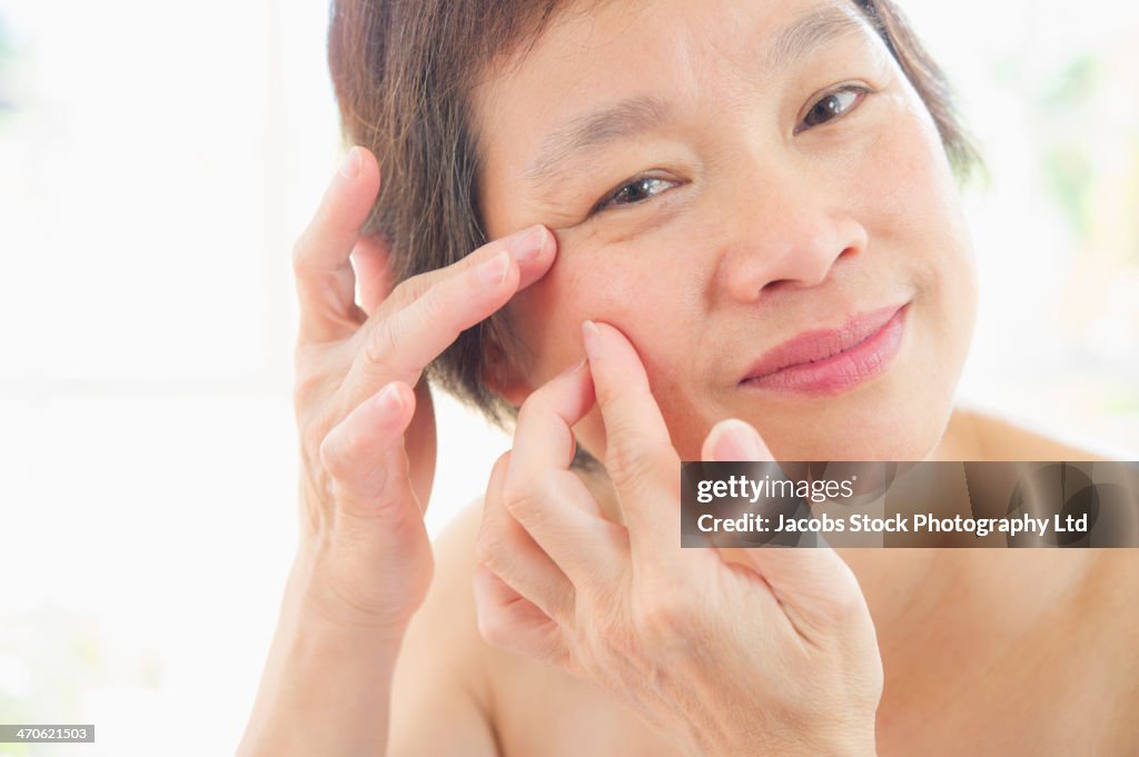 Older Chinese woman examining her wrinkles