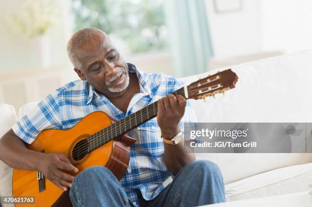 black man playing guitar on sofa - male musician stock pictures, royalty-free photos & images