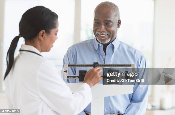 black doctor weighing patient - happiness scale stock pictures, royalty-free photos & images