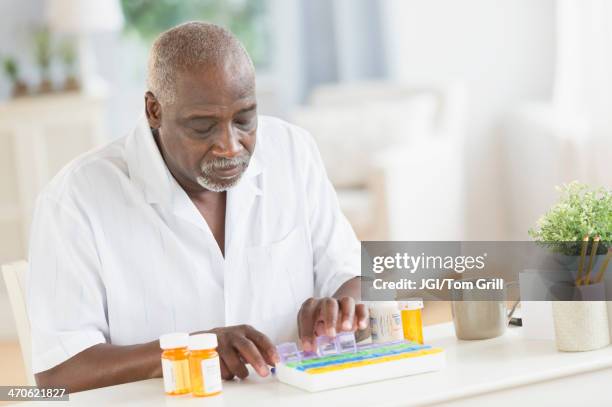 black man counting pills in pill boxes - blank pill box stock pictures, royalty-free photos & images