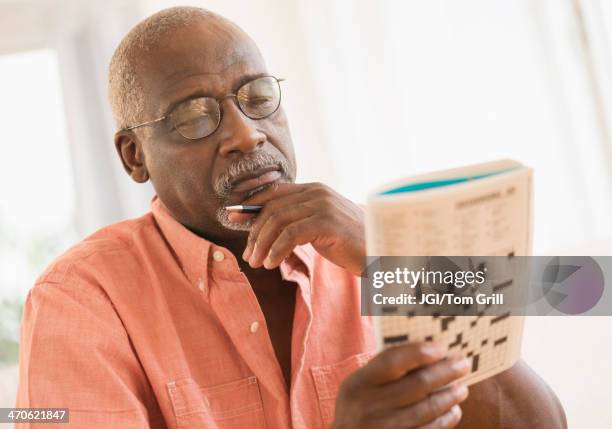 black man doing crossword puzzle - kruiswoordpuzzel stockfoto's en -beelden