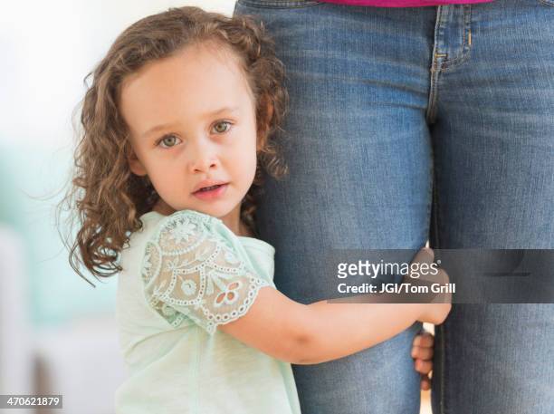 mixed race girl clinging to mother's leg - shy foto e immagini stock