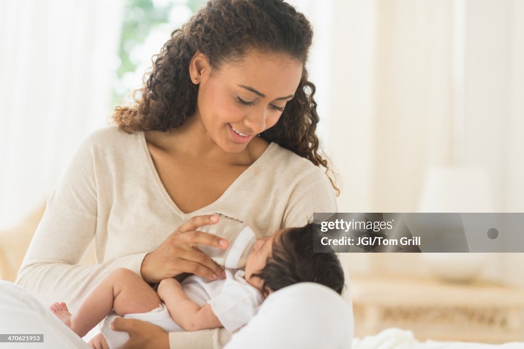 Hispanic mother feeding newborn baby