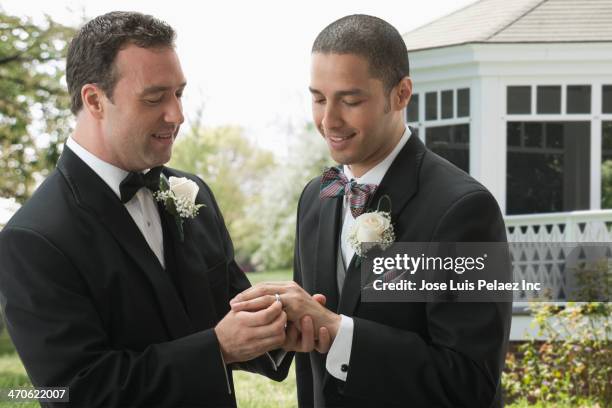 groom placing ring on husband's finger - gay marriage stock pictures, royalty-free photos & images