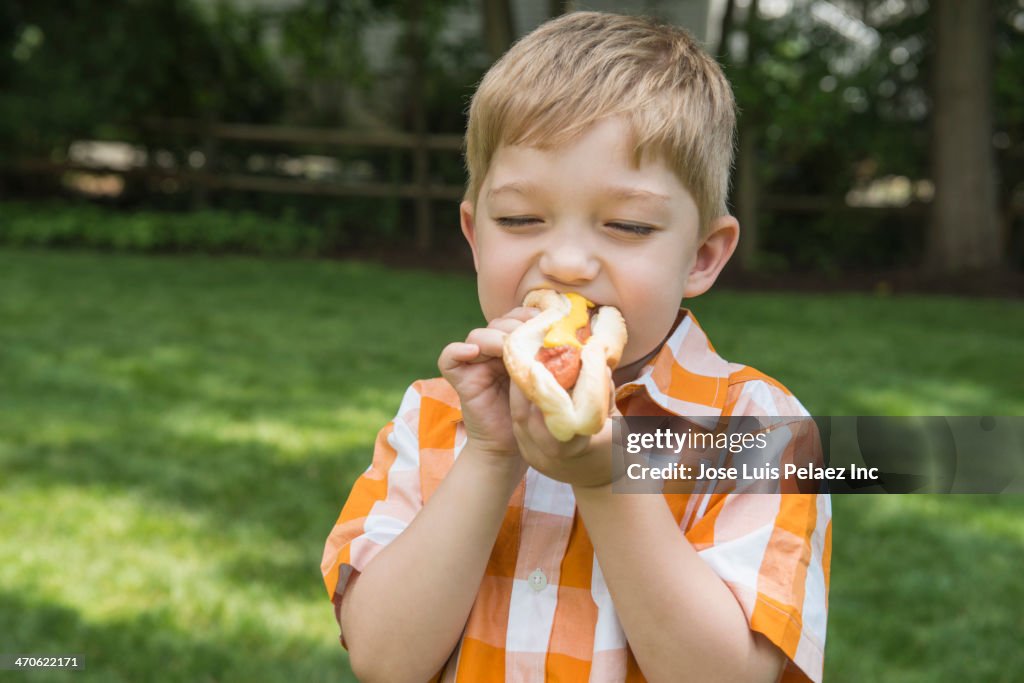 Asian boy eating hot dog