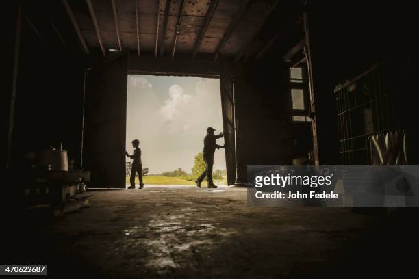 caucasian farmer and son working in barn - campagne photos et images de collection