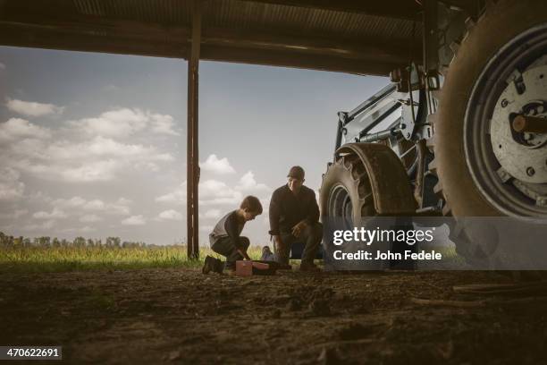 caucasian father and son working on tractor - farm family stockfoto's en -beelden