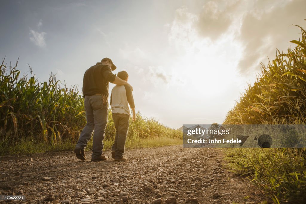 Caucasian father and son walking on dirt road through farm