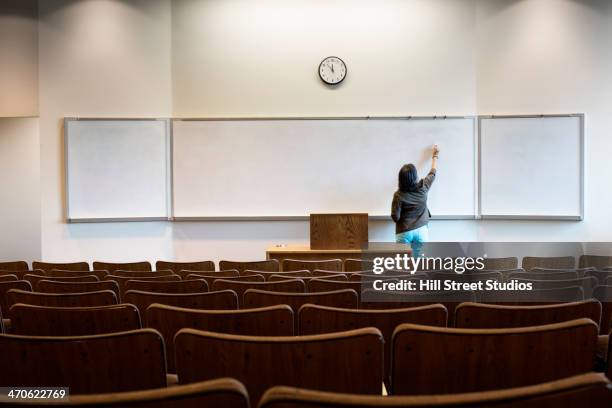 filipino professor writing on whiteboard in empty lecture hall - professor stock-fotos und bilder