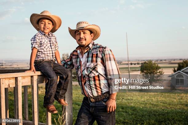 hispanic father and son wearing cowboy hats outdoors - cowboy hat imagens e fotografias de stock