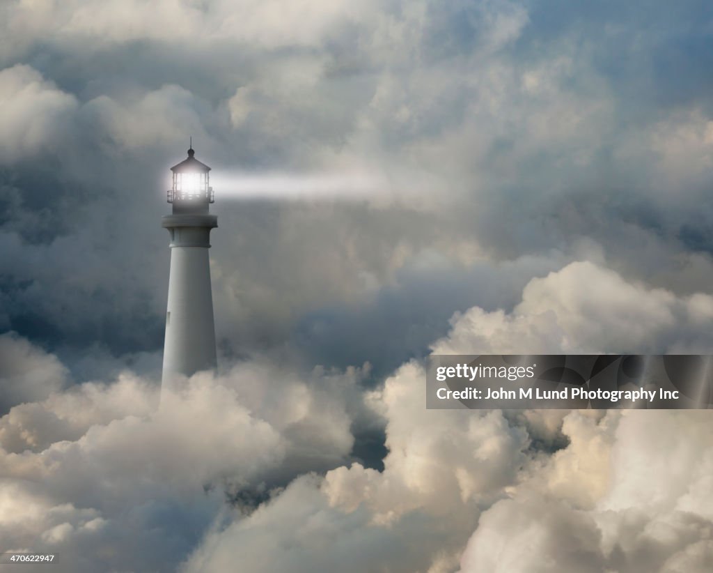 Lighthouse shining beam into thick clouds