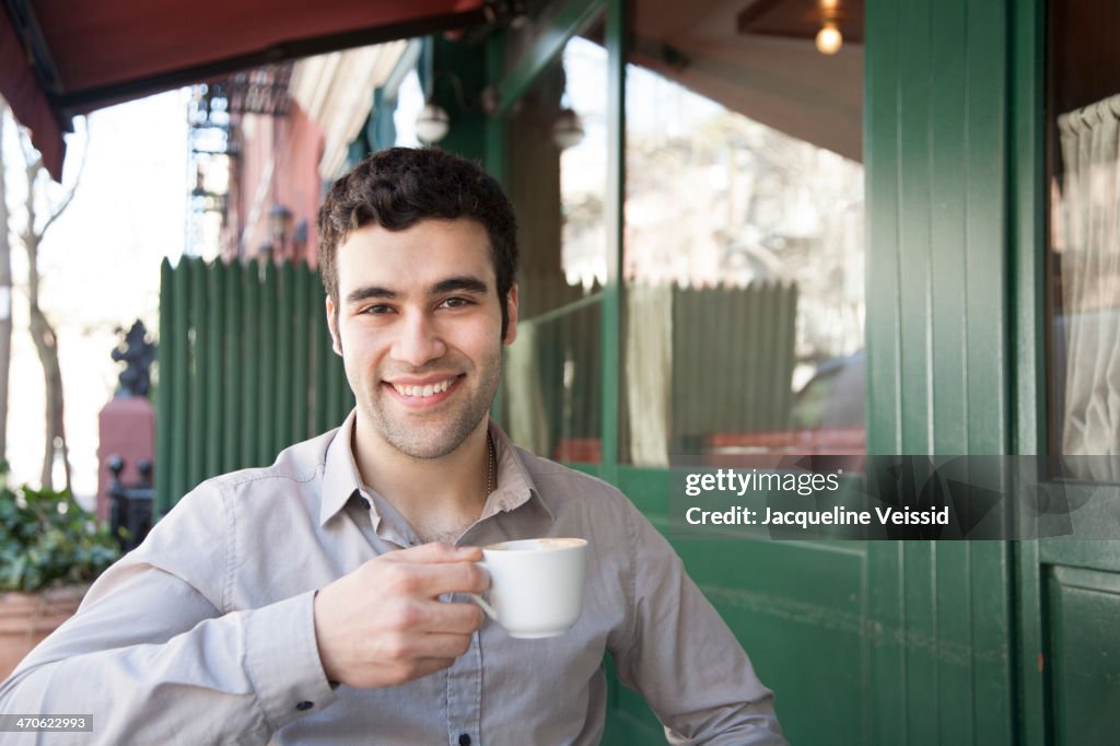 Hispanic man sitting at sidewalk cafe