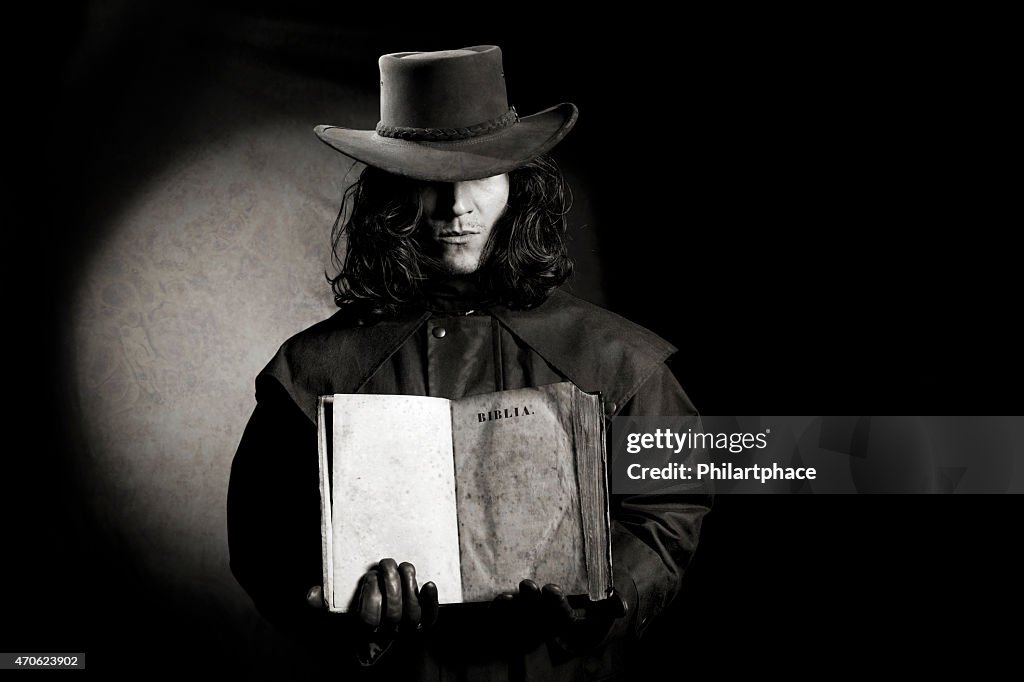 Vintage style wild west gunslinger holding ancient bible book