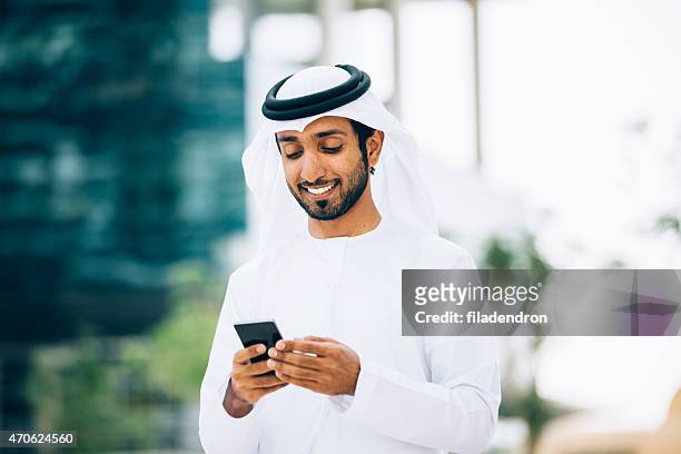emiratino utilizzando uno smart phone - emirati arabi uniti foto e immagini stock