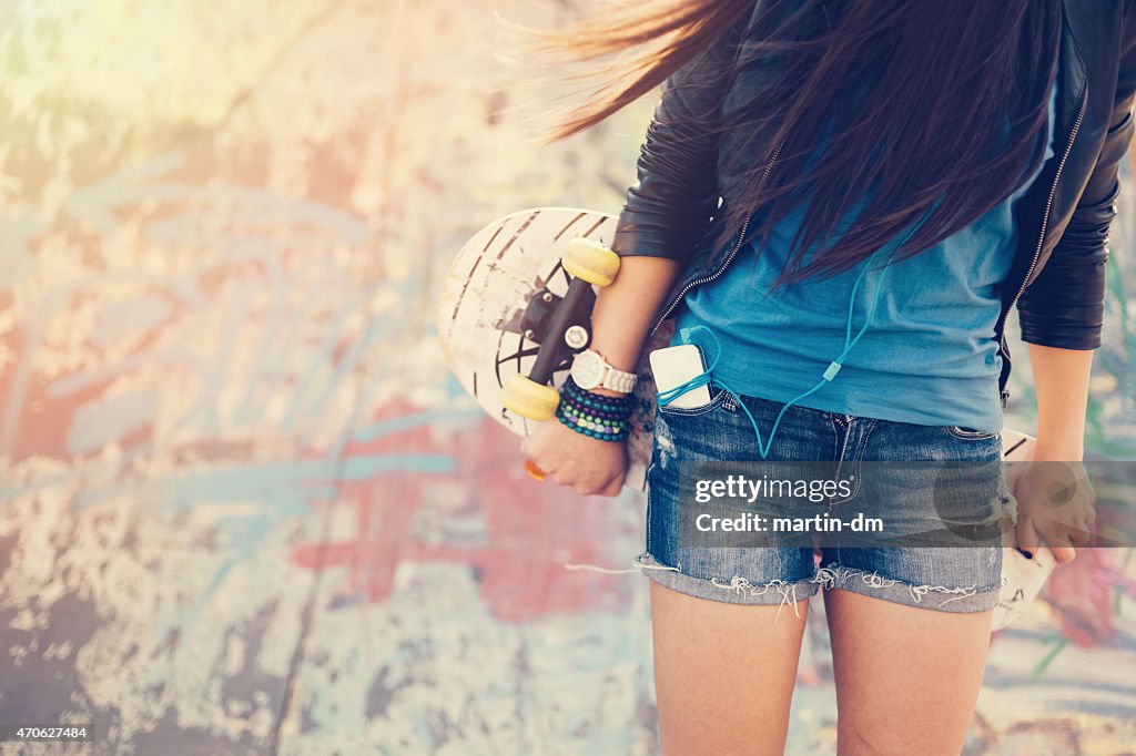 Teenage girl holding skateboard